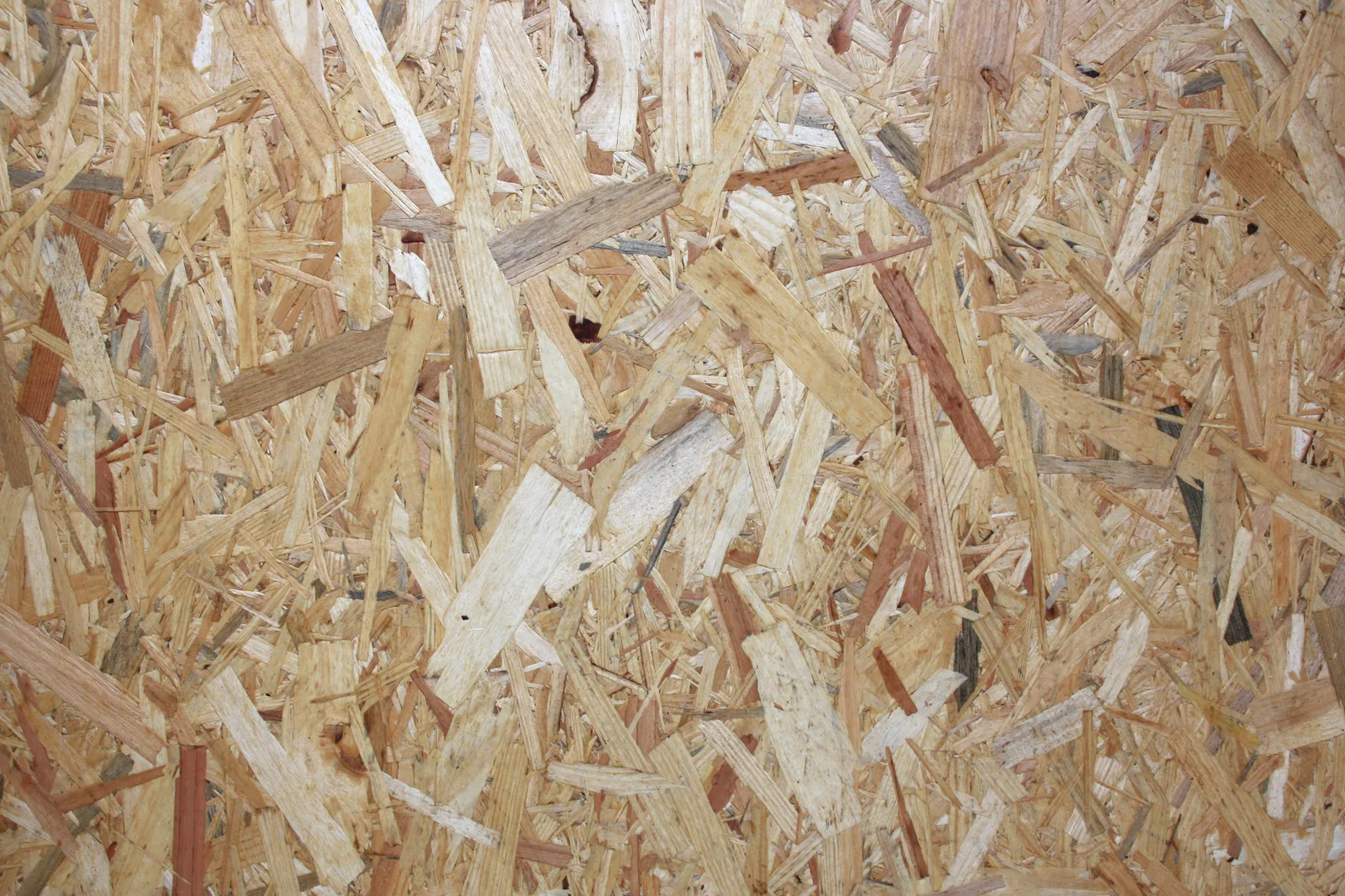 Detalhe de chapa de OSB, com lascas de madeira prensadas em diferentes direções.